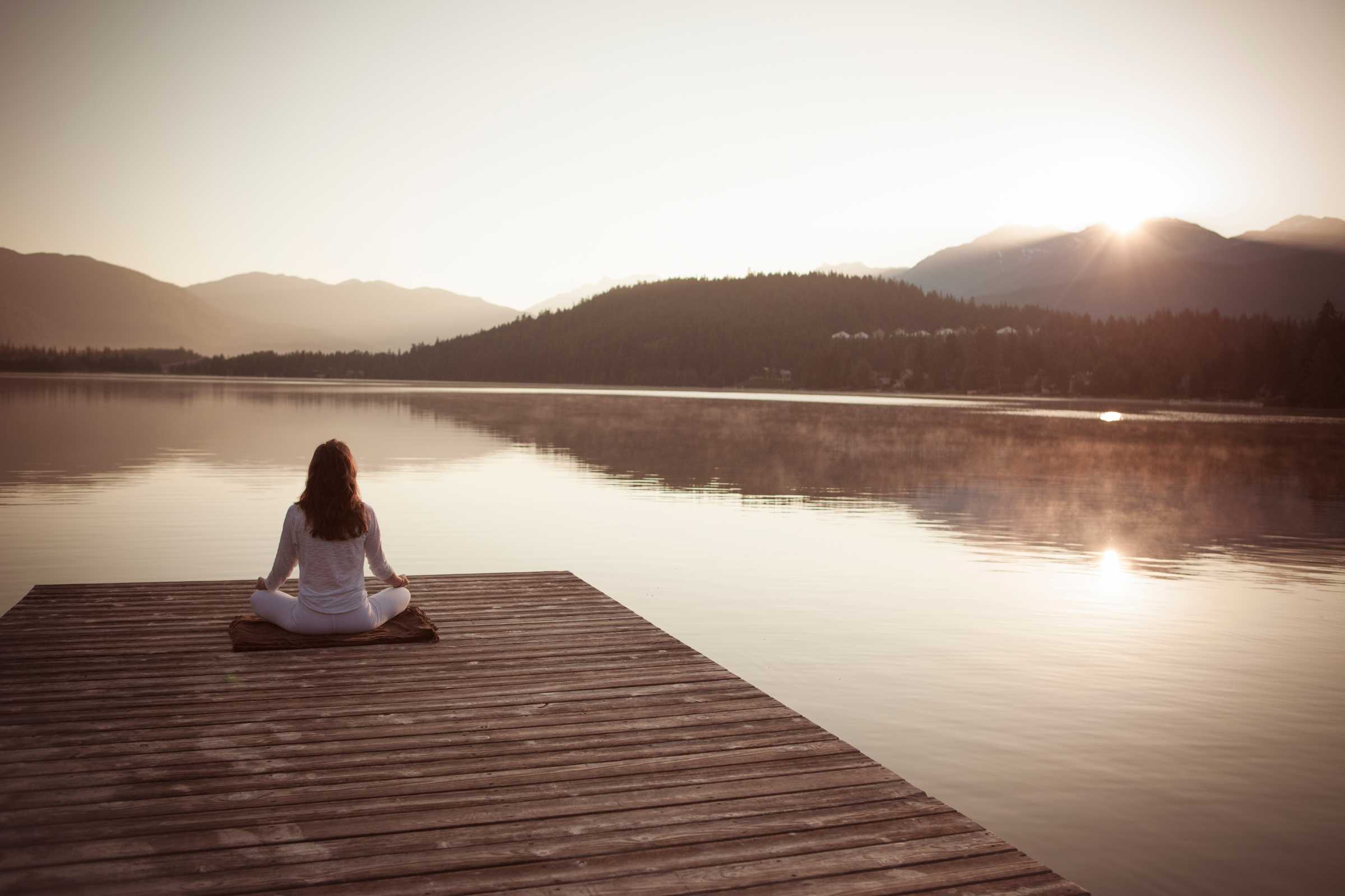 person meditating on a dock