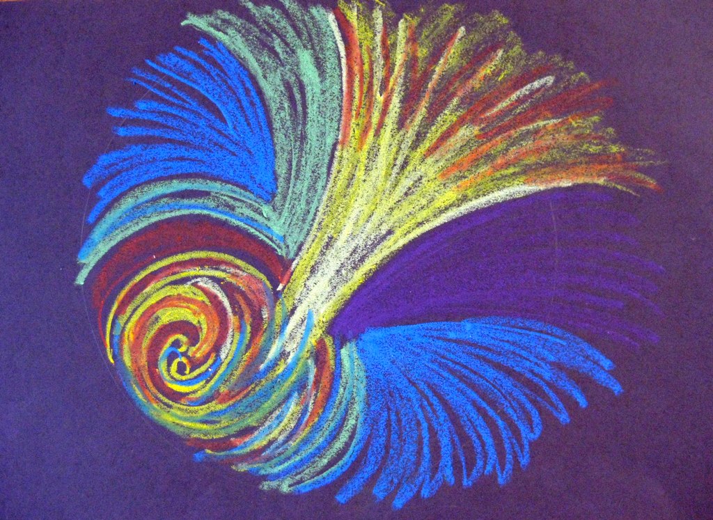 Mandala drawn with blue, yellow and orange colored pencil and pastel on dark blue paper